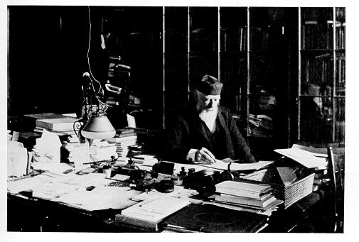 old black and white photograph of George Atherton at his desk in Old Main wearing skullcap hat