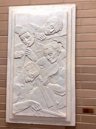 Terracotta relief by Sybil Barsky Grucci that depicts four male musicisans - three playing stringed instruments and one playing a horn
