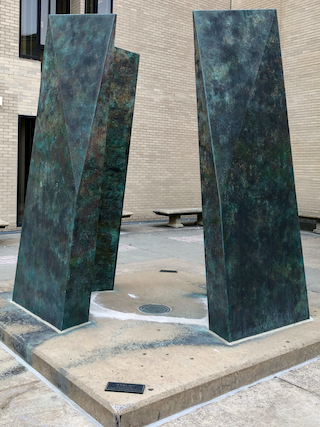 Large scale, abstract patina sculpture depicting the library stacks; it is located in the Paterno Library courtyard on Curtin Road