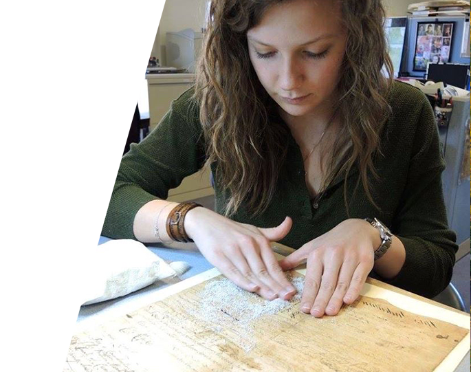 Student wearing a dark green sweater working on preserving old book pages