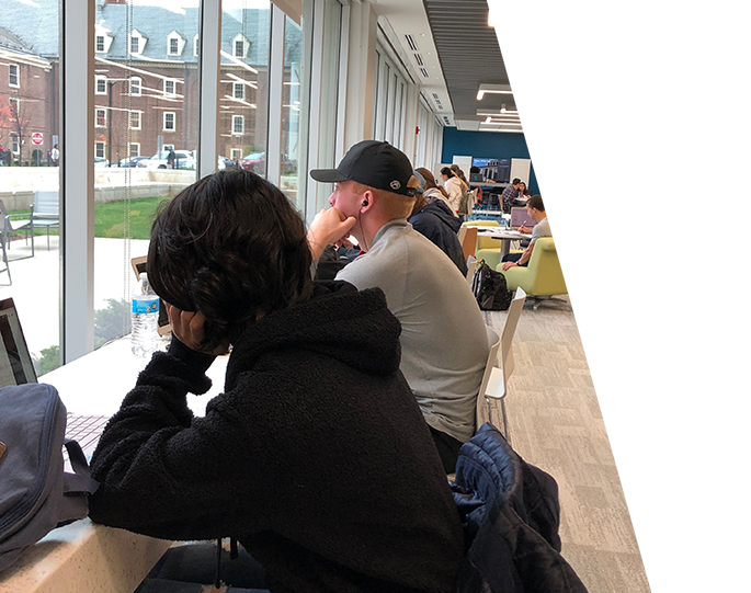 Students studying in the Collaboration Commons in front of glass windows