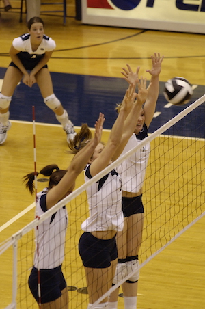 Penn State Women's Volleyball players triple blocking at the net against Ohio State's women volleyball players